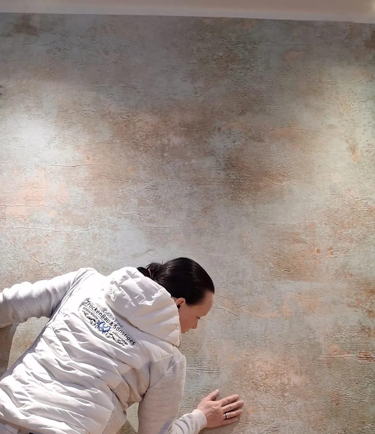 Christine Weber arbeitet von Hand an einer Wand mit Effektspachtel