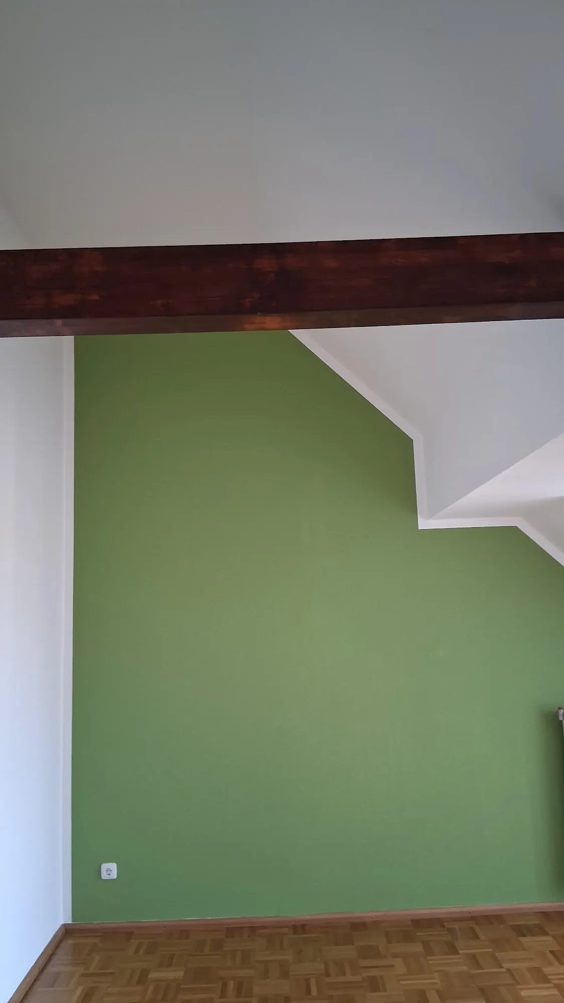 Dachgeschossraum mit grüner Wand und Holzbalken