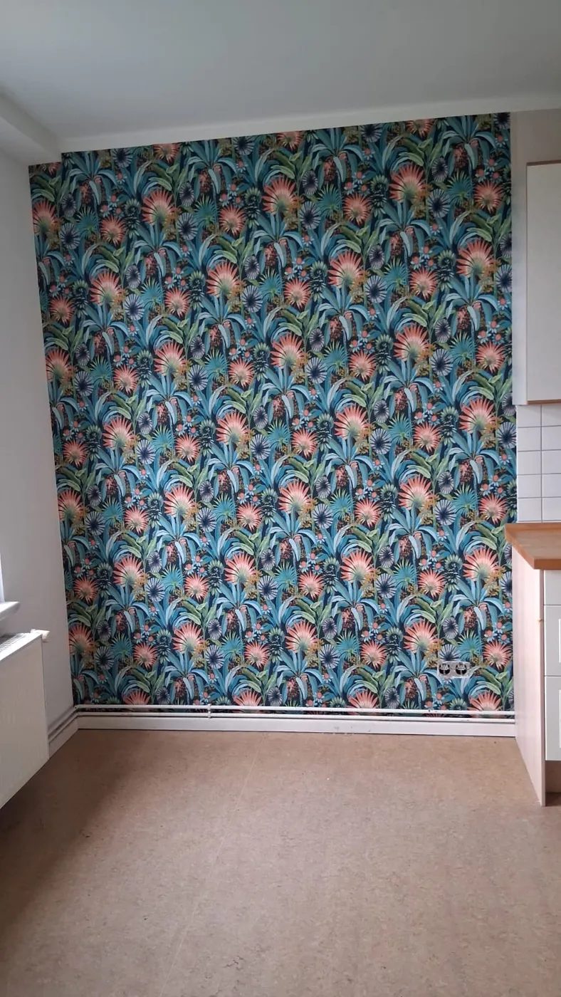Akzentwand mit tropischer Mustertapete in Blau und Koralle