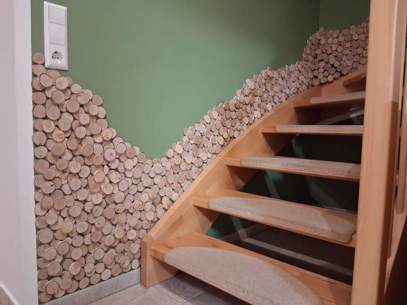 Wandgestaltung aus Holzscheiben entlang eines Treppenaufgangs