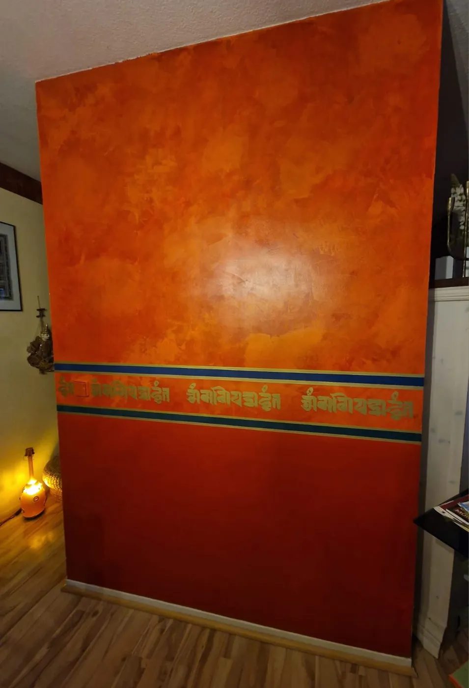 Wandgestaltung in warmem Orange mit goldenem Mantra Schriftzug